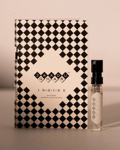 A small clear perfume spray bottle with a black atomizer cap stands beside its matching rectangular box. The packaging features a bold black and off-white diamond checkerboard pattern, with the brand name 'JAADU GHAR' and product name 'INSIDE OUT' printed in the center.